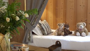 A cozy bedroom with a wooden headboard, a bedside table with a mug, a small plant, and two teddy bears on the bed. - Les Fermes de Pierre et Anna (Le Grand-Bornand)