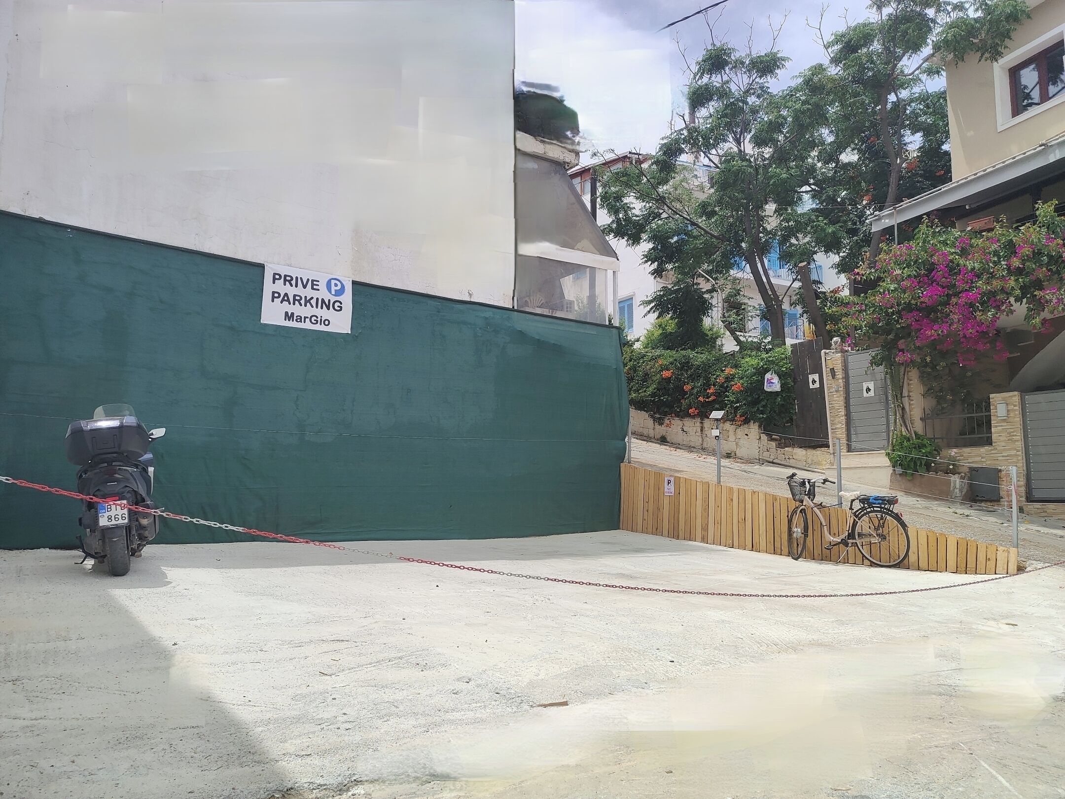 A private parking area with a motorcycle parked, a bicycle, and a sign indicating 'PRIVE PARKING MarGio'.