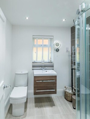 A compact bathroom with a toilet, a sink with a mirror, and a glass shower enclosure.