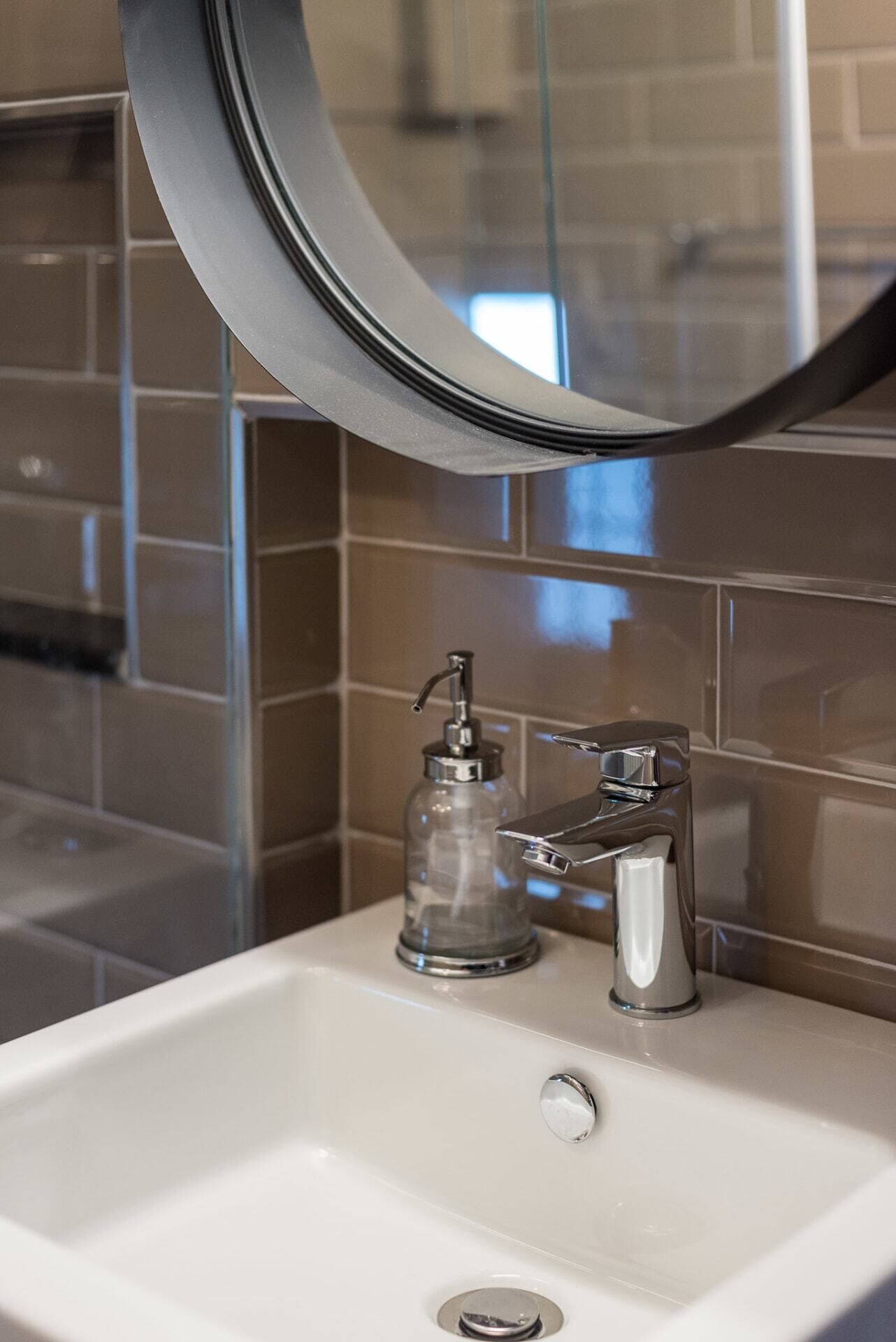 A bathroom sink with a chrome faucet and a soap dispenser.