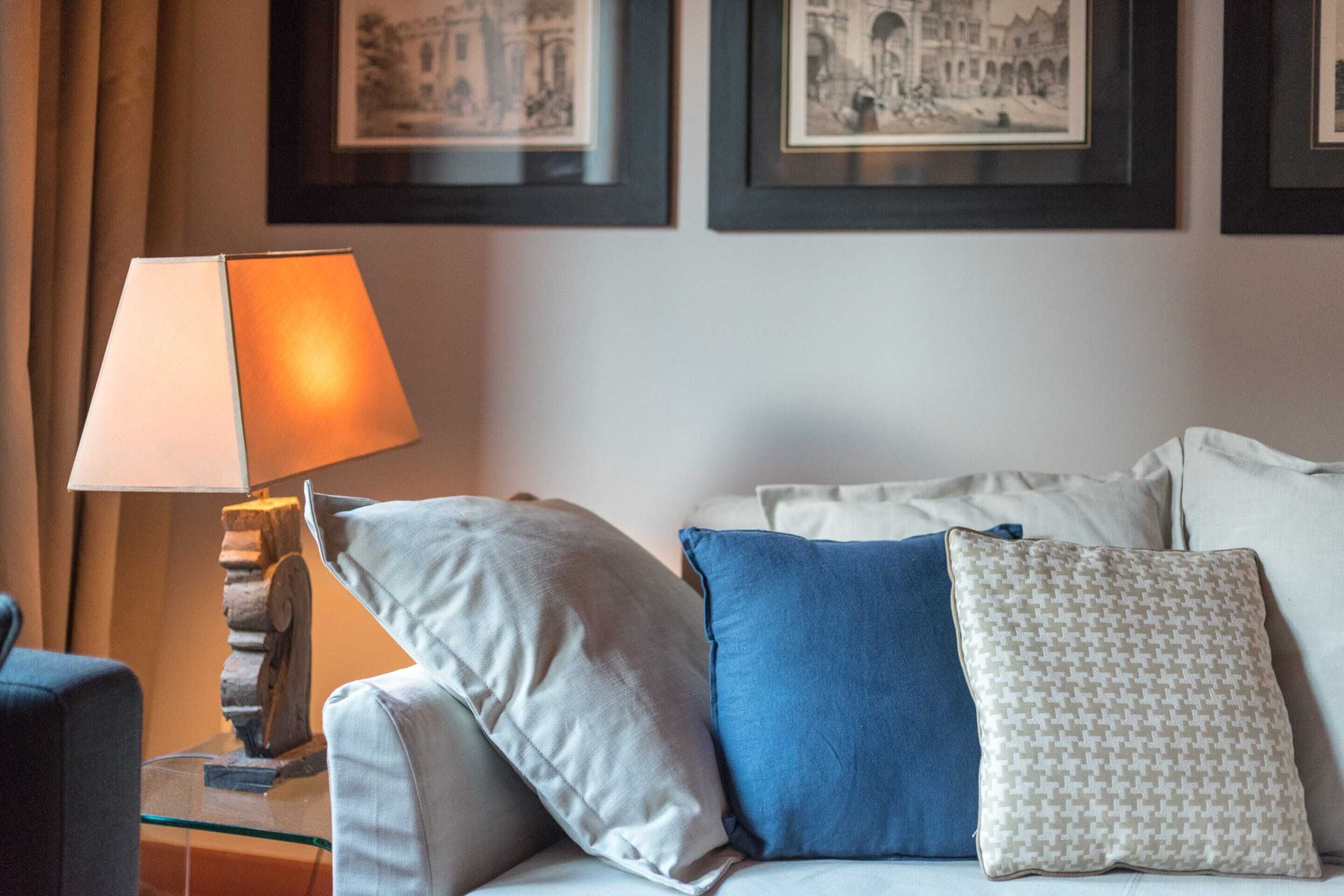Habitación de hotel con sofá, lámpara y cuadros en la pared.