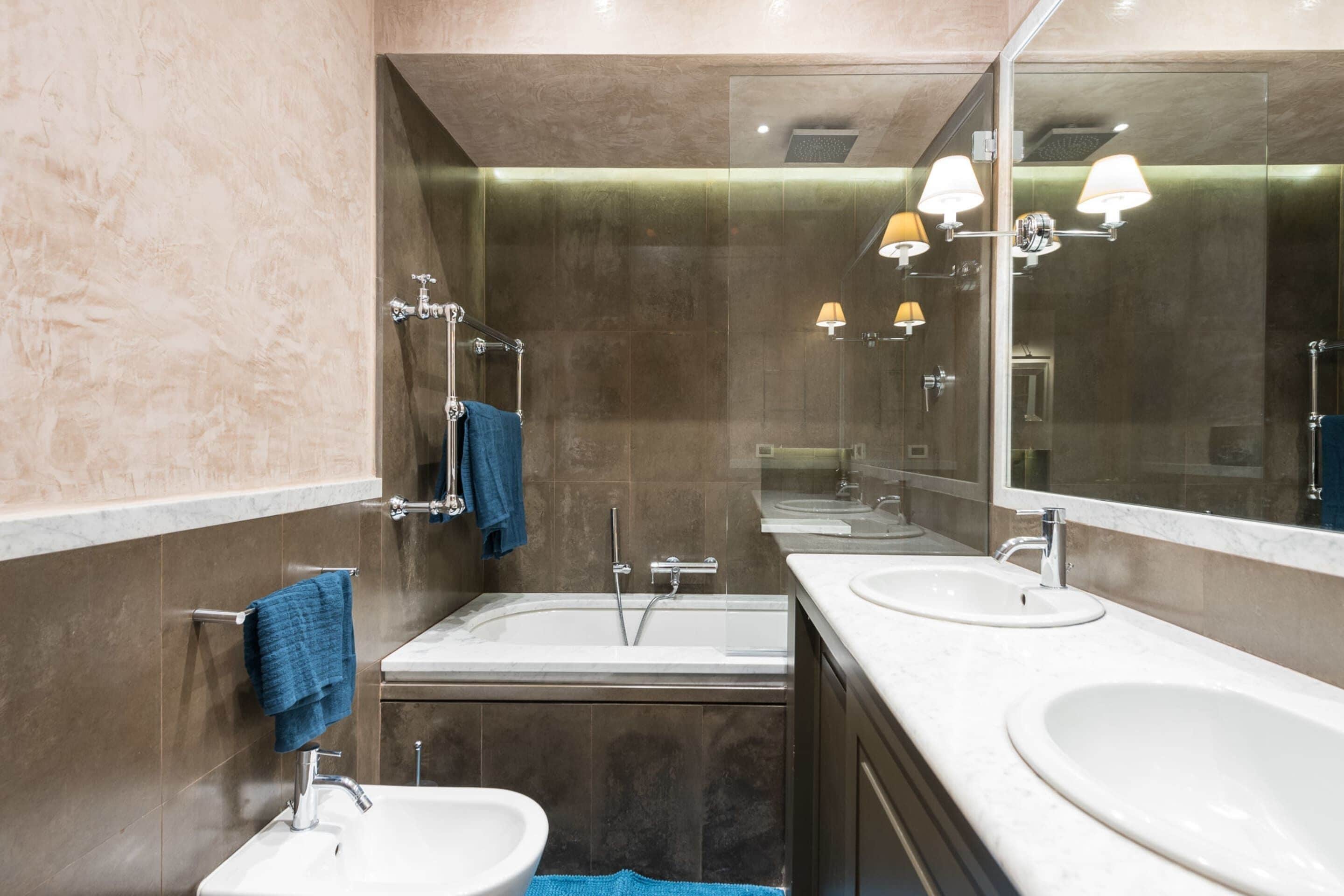 A modern bathroom with two sinks, a bathtub, and a large mirror.