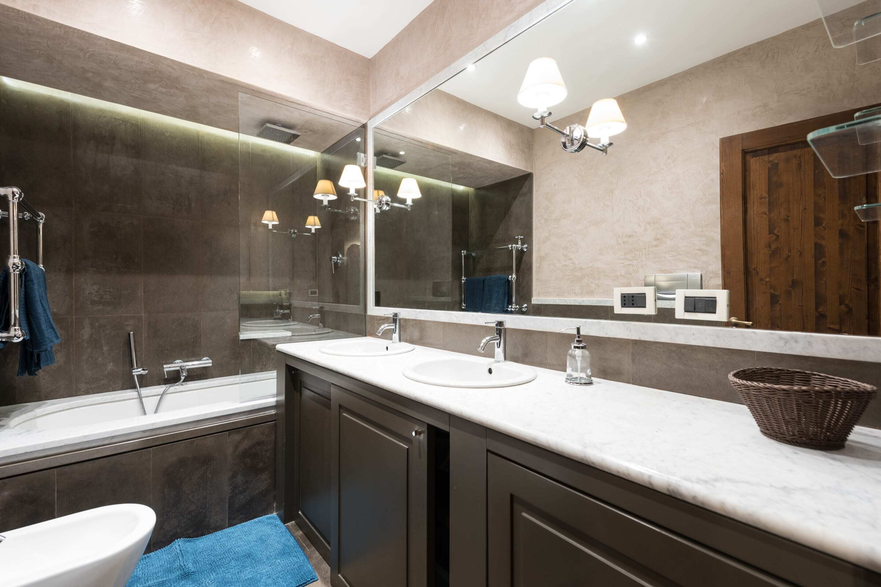 Une salle de bain moderne avec un grand miroir, deux lavabos, une baignoire et une douche.