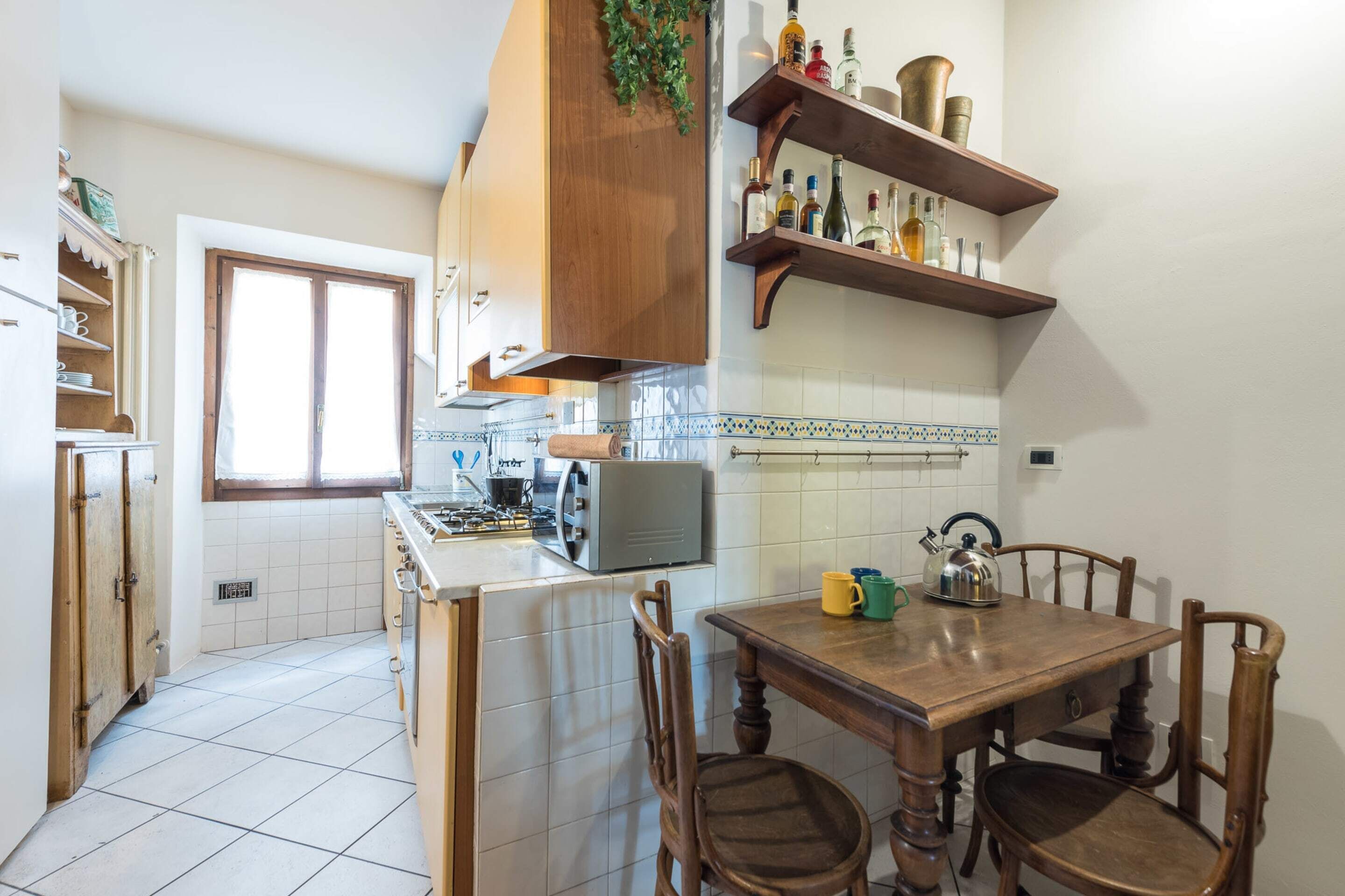 Una cocina con armarios de madera, estufa, microondas y una mesa de comedor con sillas.