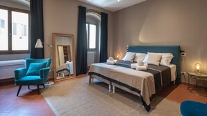 Un dormitorio con cama, una silla, un espejo y una ventana.