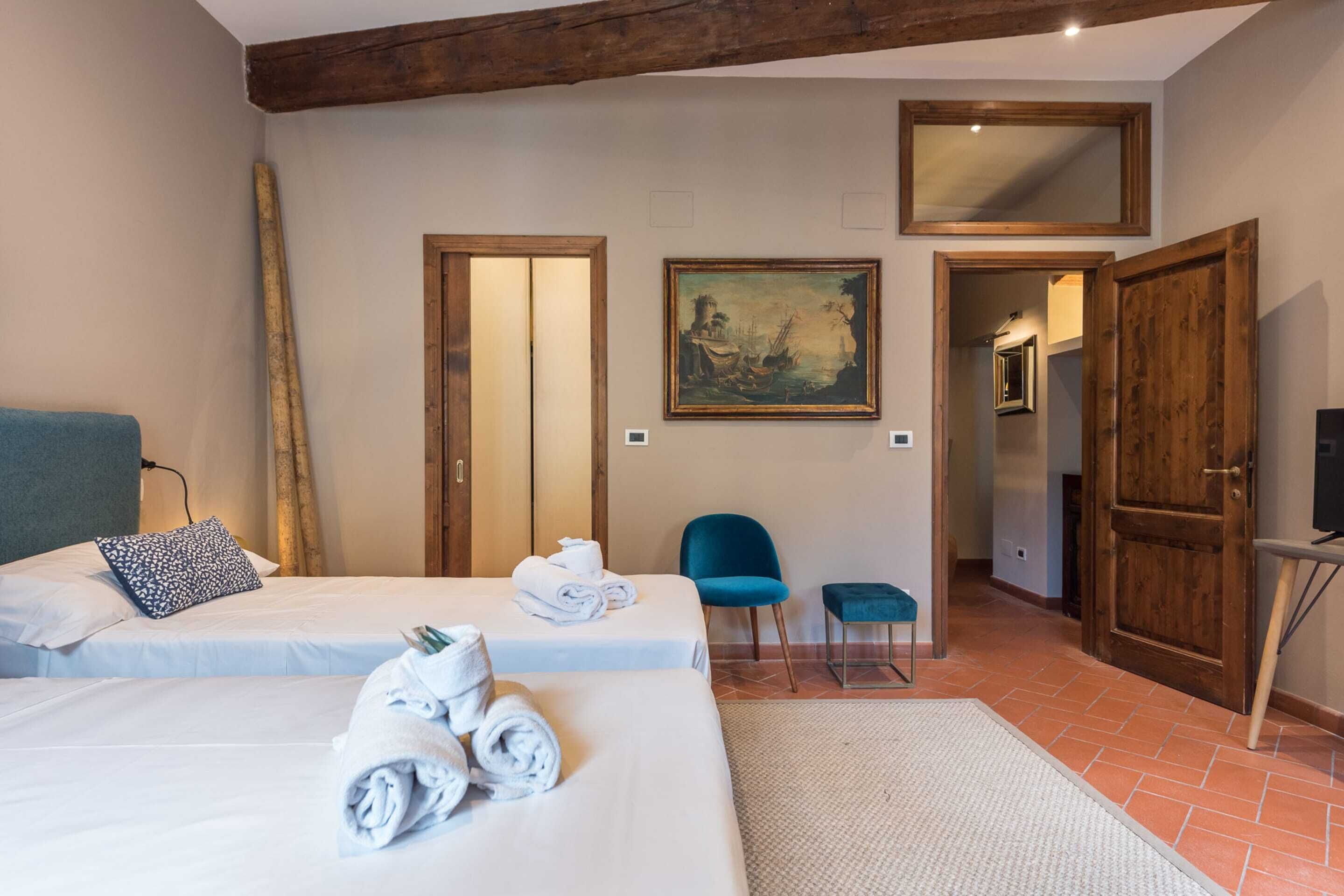 Een hotelkamer met twee bedden, een schilderij, een spiegel en een houten deur.
