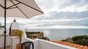 Eine Terrasse mit Tisch, Stühlen und einer Weinflasche.