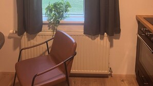 Una habitación con ventana, una silla, un radiador y una estufa.