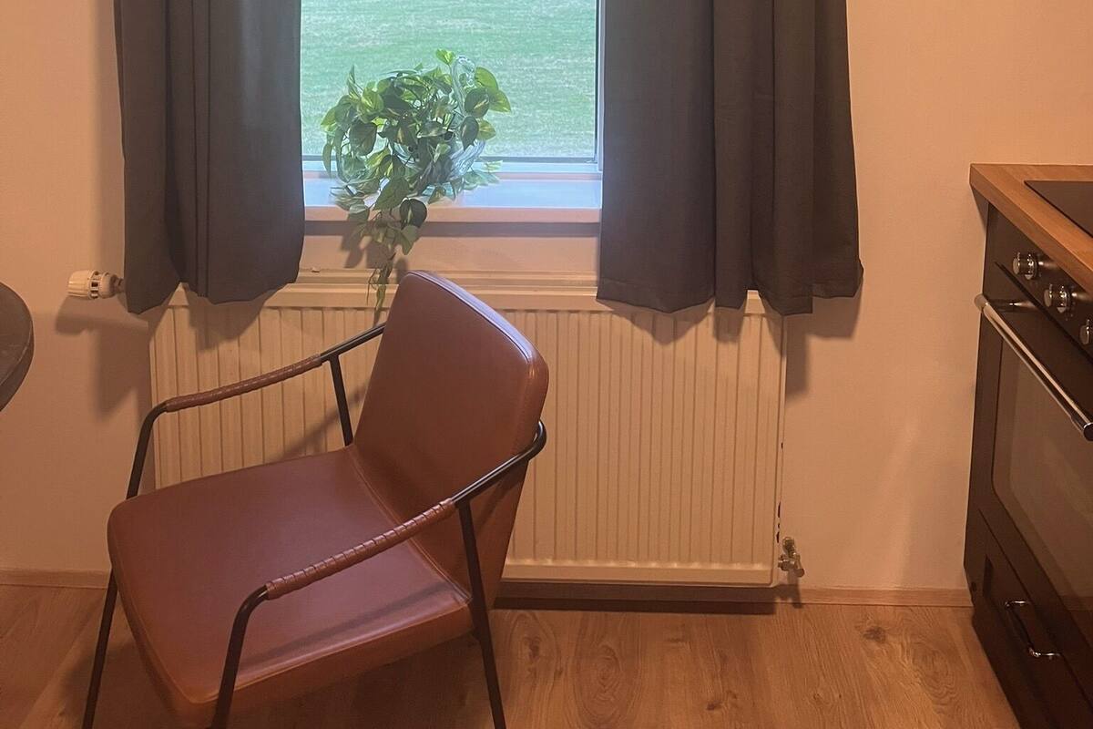 Ein Zimmer mit Fenster, einem Stuhl, einer Heizung und einem Herd.