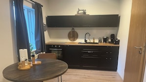 Una cocina compacta con una mesa redonda de comedor, electrodomésticos integrados y piso de madera.