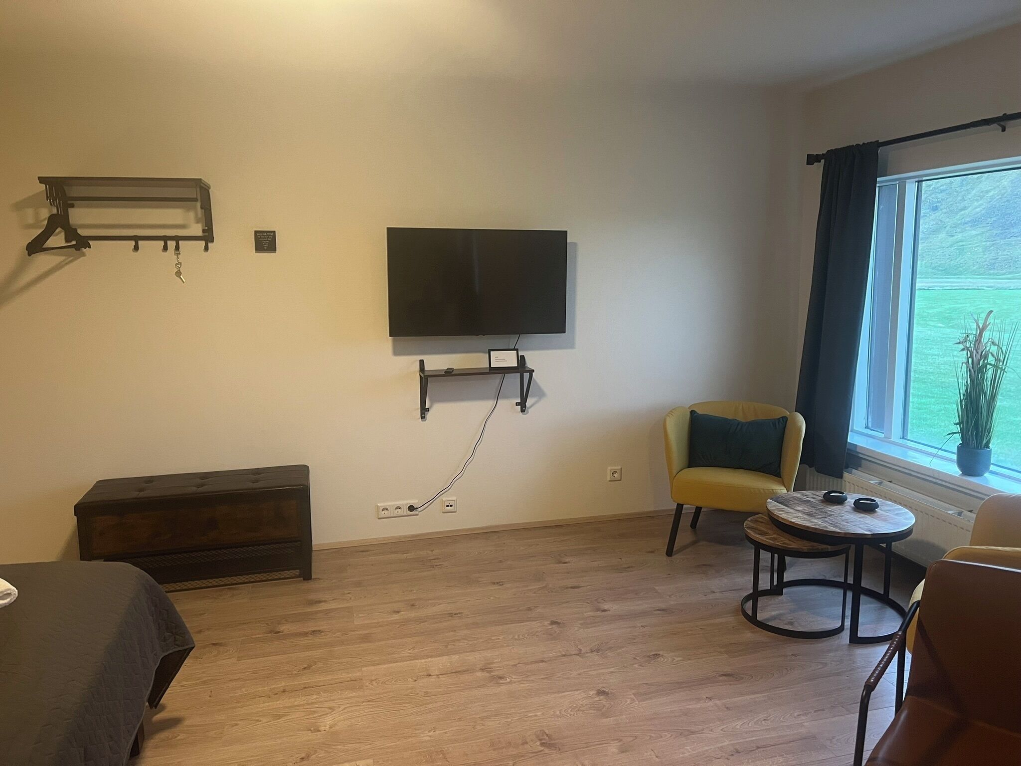 Une pièce comprenant un lit, un canapé, une petite table, un téléviseur fixé au mur et une fenêtre donnant sur un paysage verdoyant.