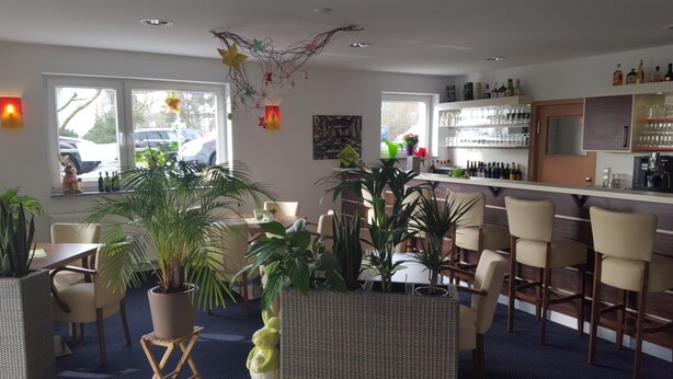 A bar area with seating, a counter with bottles, and decorative elements. - Hotel Beuss (Oberursel)