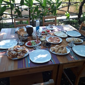 An outdoor dining table set with various dishes, including bread, salads, and plates of food. - Teo Hotel (Kemer)