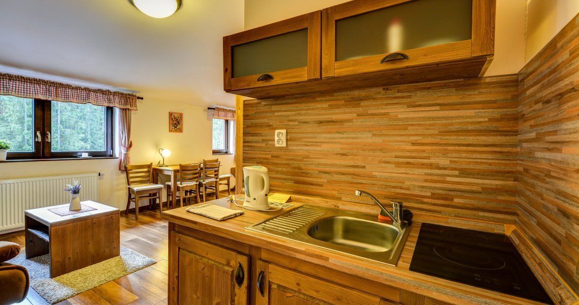 A compact kitchen with wooden cabinets, a built-in stove, and a window overlooking a forest.
