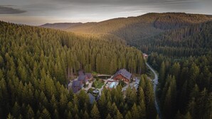 A lodge surrounded by dense forest with a clear view of the mountains in the background. - Wellness Hotel Ondrášův Dvůr (Bílá)