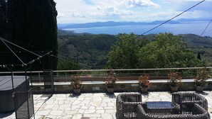Una terraza con suelo de piedra, muebles de mimbre y plantas en macetas.