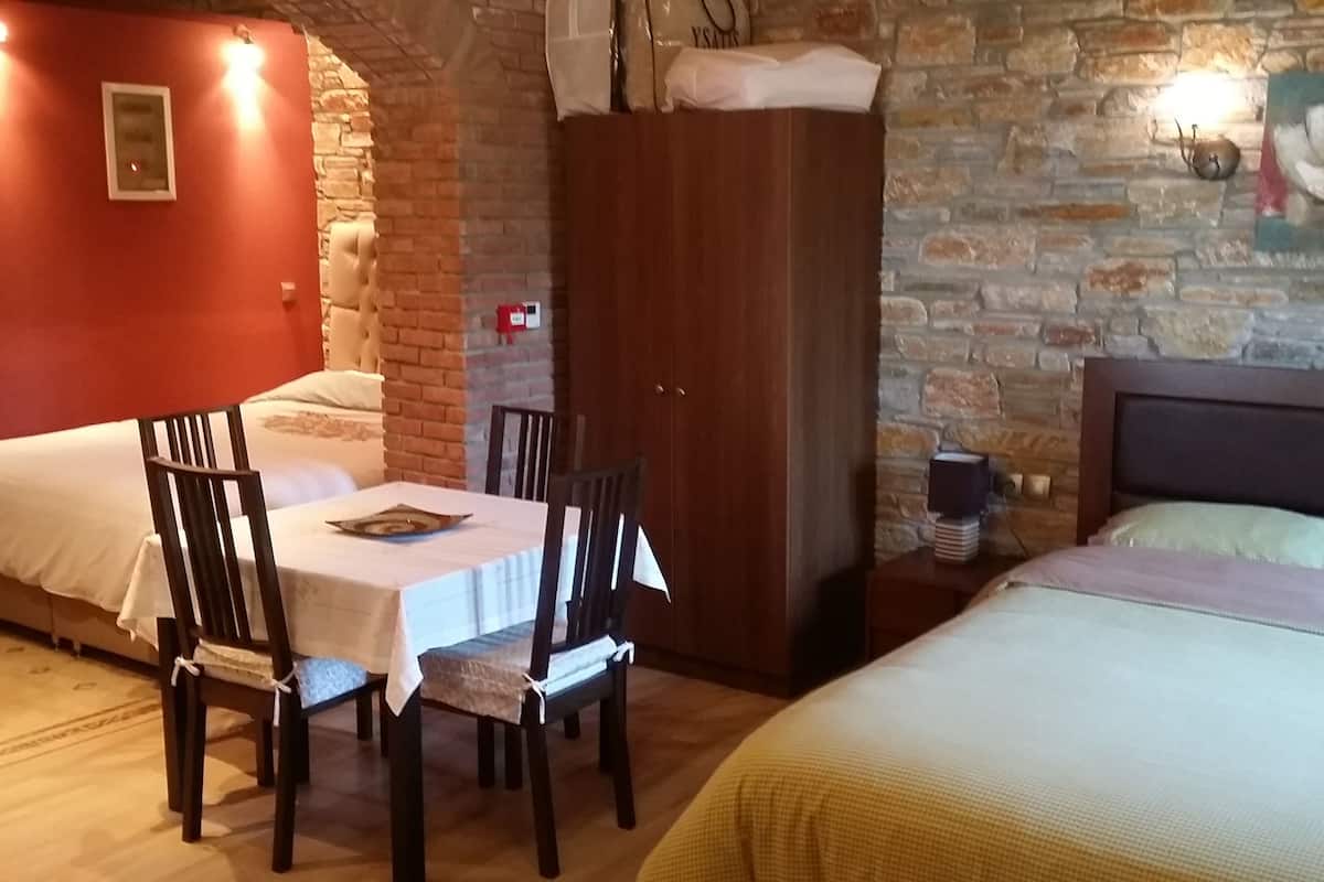 Una habitación acogedora con cama, una mesa con sillas, un armario y una pared de ladrillo.