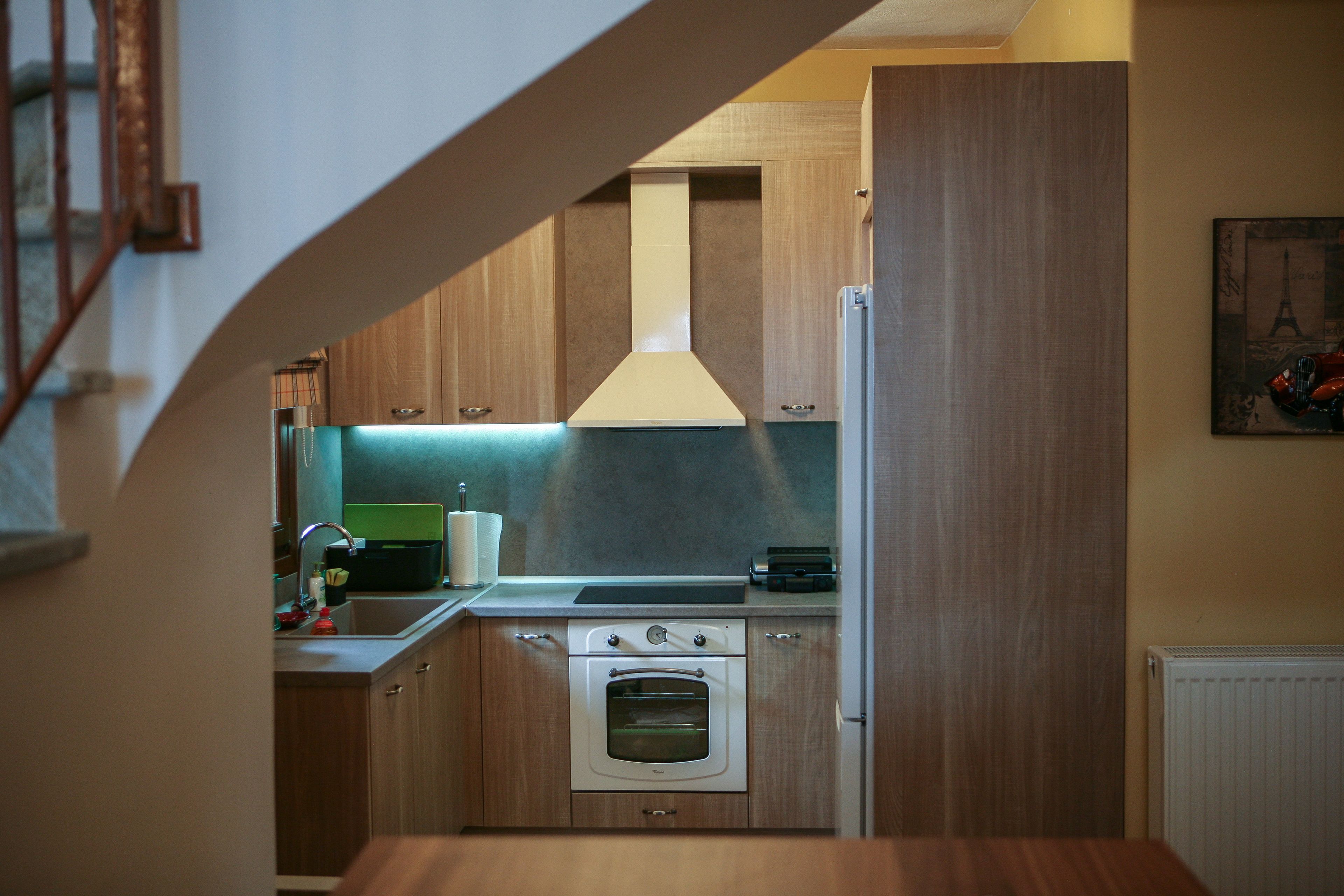 Eine kleine Küche mit Holzausstattung, einem eingebauten Backofen und einem Edelstahlspülbecken.