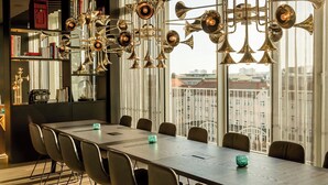 Un espace repas moderne avec une longue table, des chaises et un lustre décoratif en laiton.