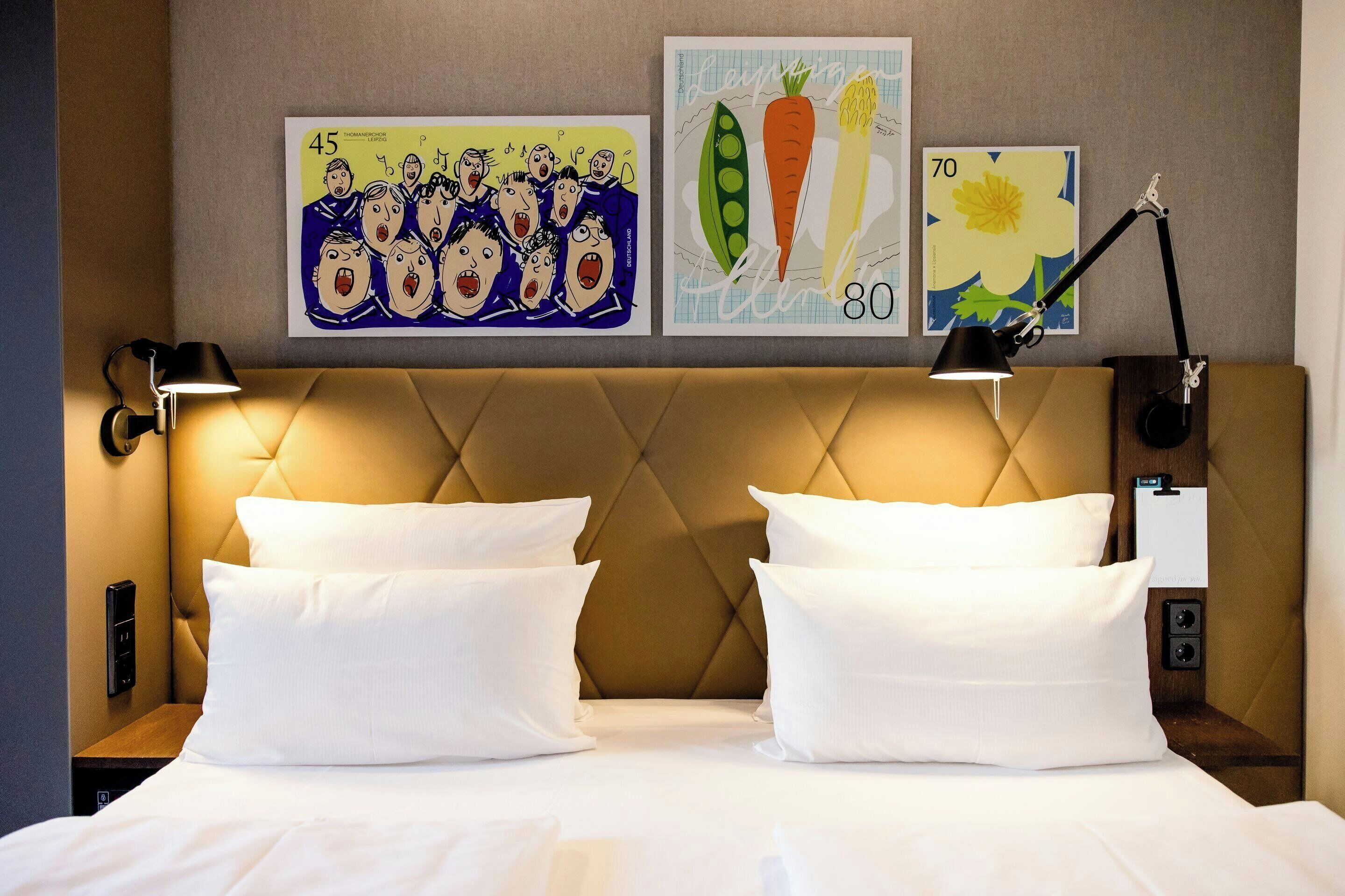 Una habitación de hotel con una cama grande, dos lámparas de noche y cuadros en la pared.