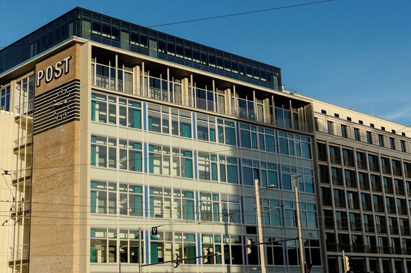 A modern building with a prominent 'POST' sign on the facade, featuring multiple floors with large windows and a glass section on the upper level.