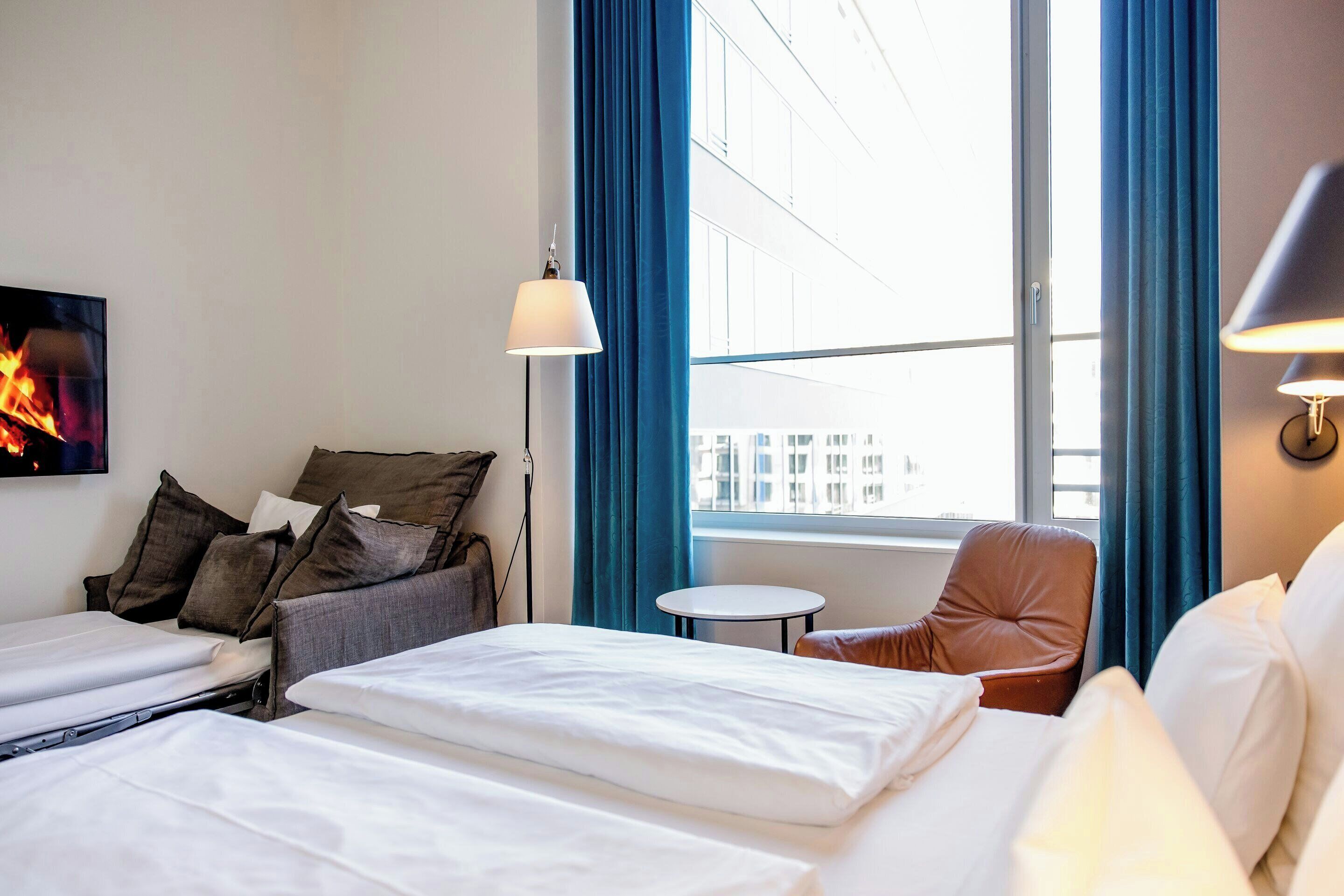 Una habitación de hotel con una cama, una silla, una mesita y un televisor.