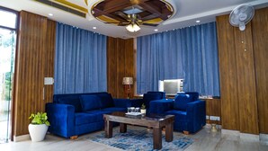 A modern living room with a blue sofa set, a wooden coffee table, and a ceiling fan. - Swasno By Rivlet (Gurugram)