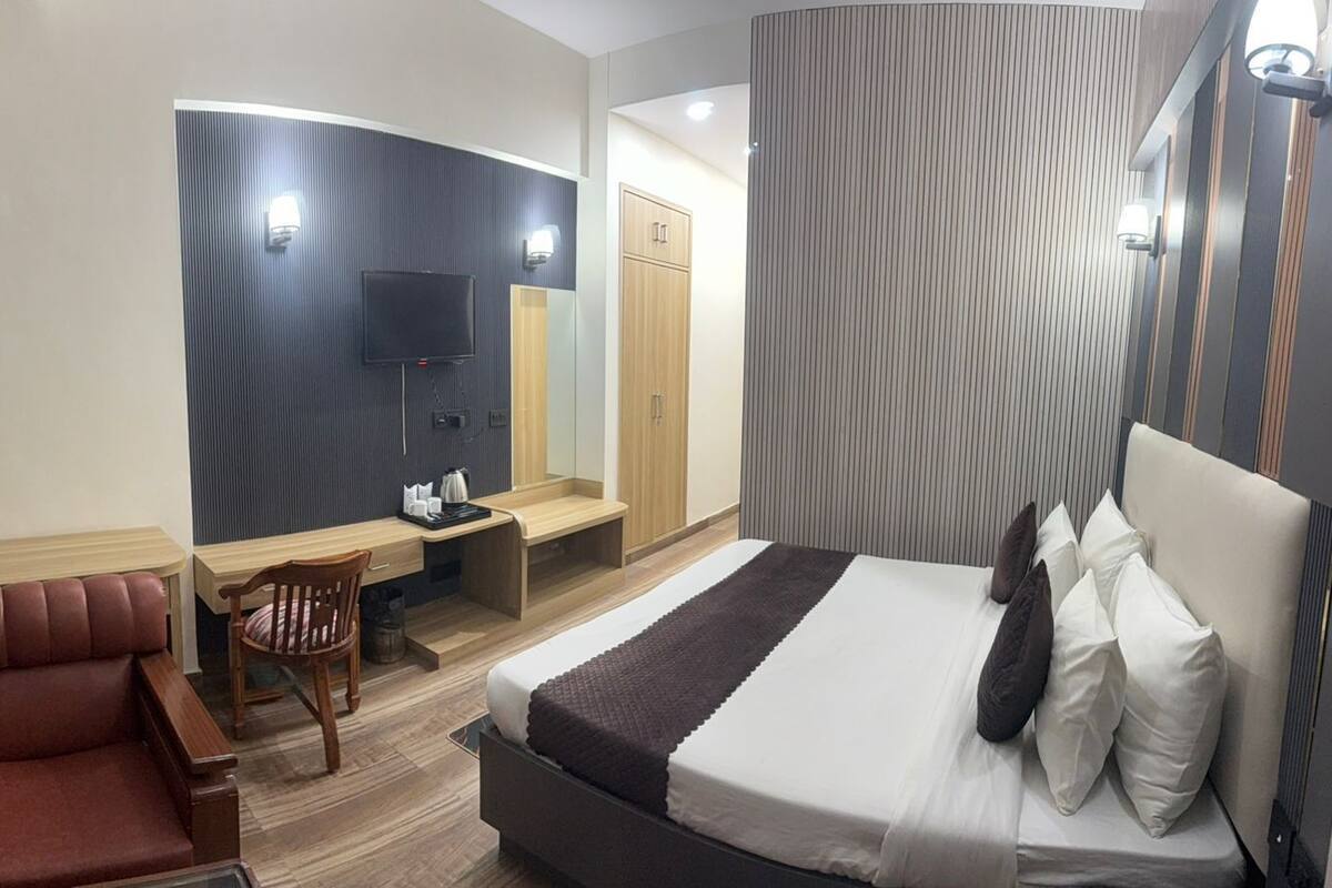 A hotel room with a bed, a desk, a chair, and a television.