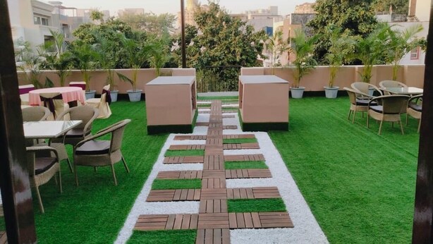 A rooftop patio with outdoor seating, a central pathway, and surrounding greenery. - Swasno By Rivlet (Gurugram)