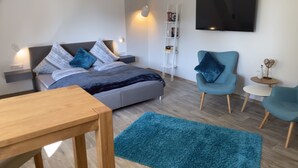 A modern bedroom with a bed, bedside tables, a desk, and a chair.