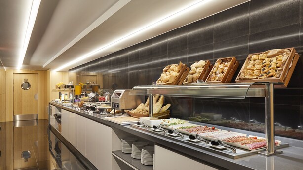 A buffet with various food items and a wooden door on the left. - Dorma Plaza Catalunya (Barcelona)