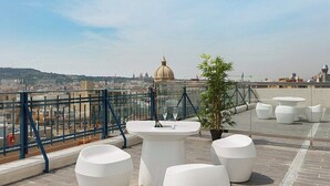 Una terraza en la azotea con vistas despejadas de un paisaje urbano, incluyendo una cúpula destacada.