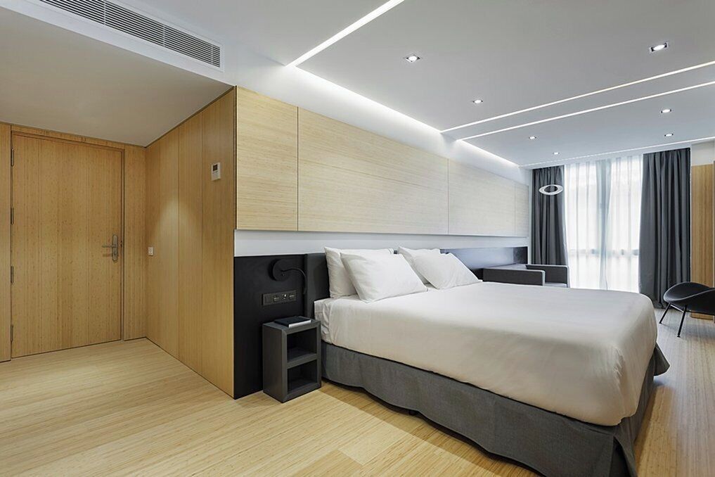 Een moderne hotelkamer met een groot bed, een kast, een nachtkastje en een bureau.
