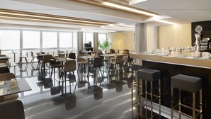 Un restaurante moderno con una barra alargada, taburetes y sillas altas.