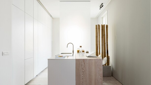A modern bathroom with a wooden vanity, a sink, and a mirror. There are bamboo sticks on the wall and a small plant on the floor. - Home at Hotel Boccherini luxury studio (Milan)