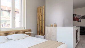 A modern bedroom with a bed, a bedside table, a window, and a view of buildings outside. - Home at Hotel Boccherini luxury studio (Milan)