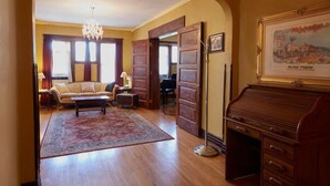 Un amplio salón con un escritorio grande de madera, un sofá y una araña.