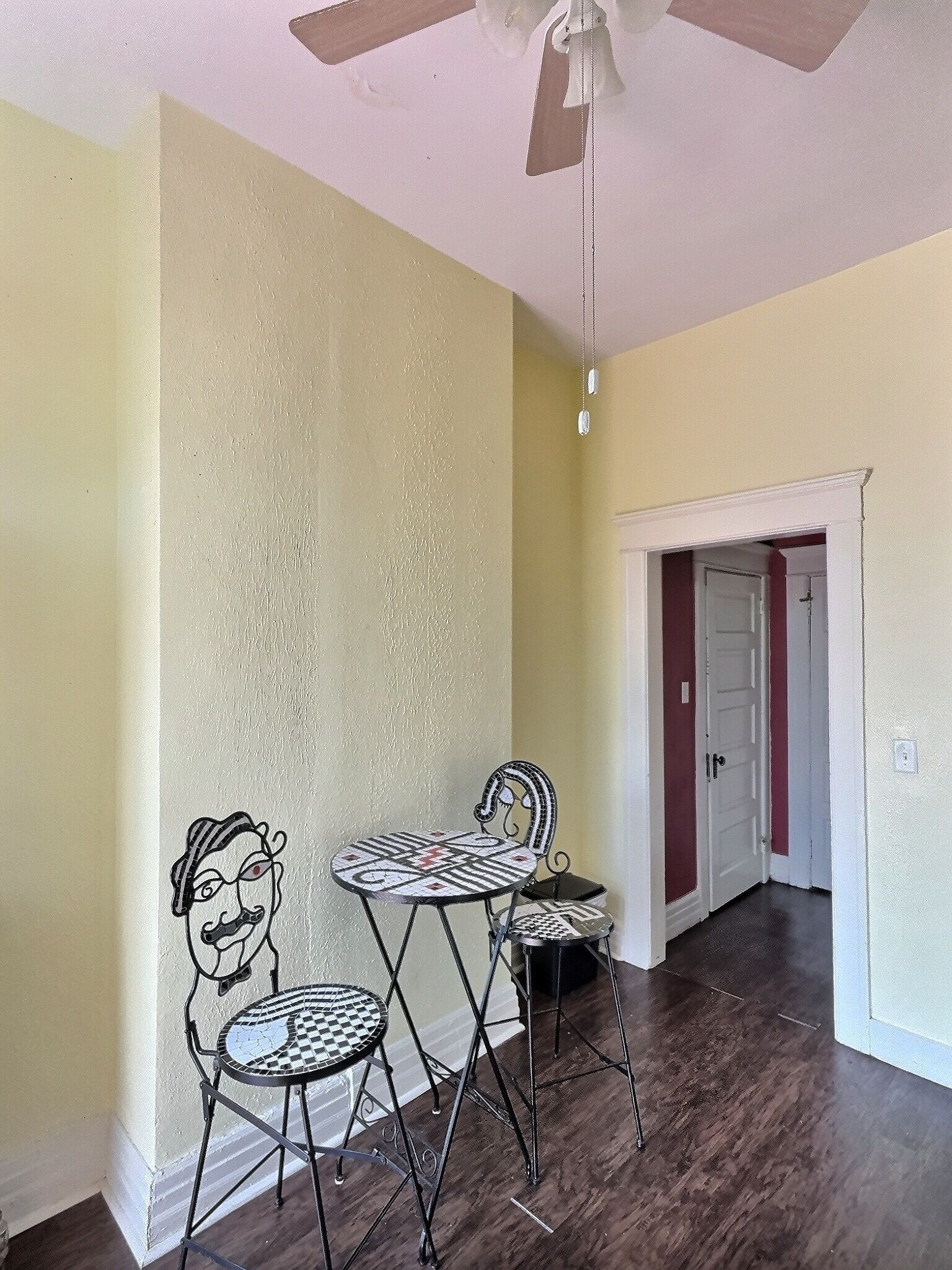 A dining area with a ceiling fan, a patterned table, and two chairs.