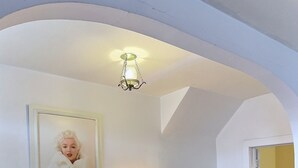 Un comedor con una mesa redonda de vidrio, dos sillas, una lámpara y un cuadro en la pared.