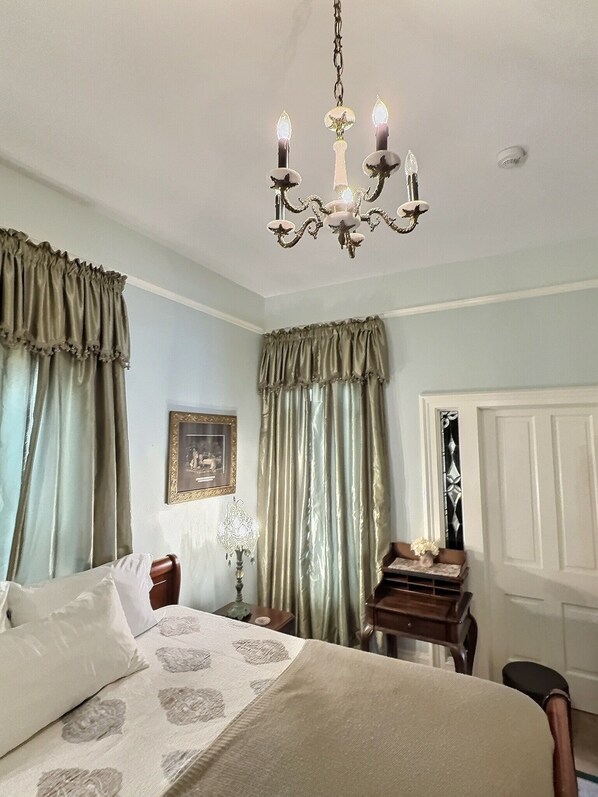 A bedroom with a bed, a nightstand, a dresser, and a chandelier.