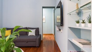 A modern living room with a grey sofa, a flat-screen TV mounted on the wall, and a wooden floor. - Home at Hotel Naviglio - Sambuco Apt (Milan)