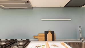 A kitchen with a gas stove, a wooden cutting board, a rolling pin, and a recipe book on the counter. - Home at Hotel Naviglio - Sambuco Apt (Milan)
