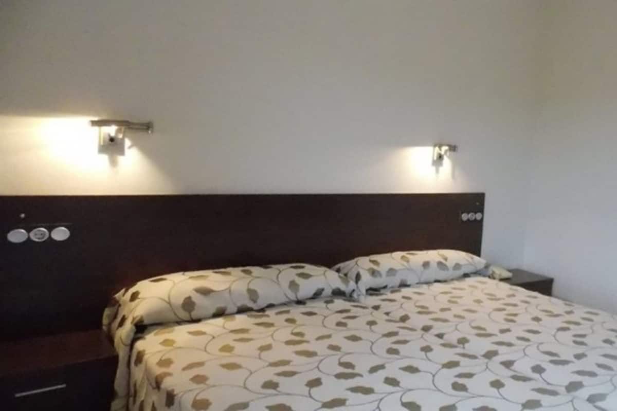 Une chambre à coucher avec un lit, deux tables de chevet et deux lampes fixées au mur.