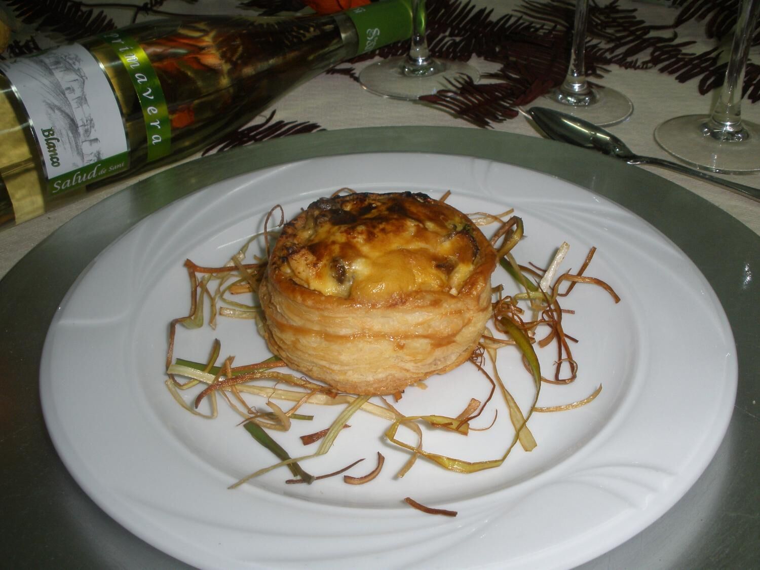 Un plato con un pastel sobre una superficie blanca, rodeado de verduras en rodajas finas.