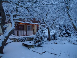 A snow-covered house with a wooden porch and a stone bench. - Ferienhaus Hagenwinkel (Quedlinburg)