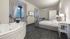 A hotel room with a bathtub, a bed, a desk, and a window with curtains. - Hotel le Macine (Montaione)