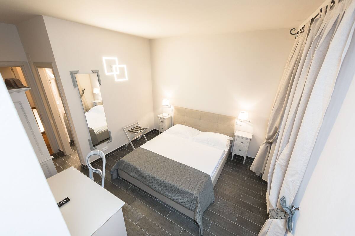 Ein Hotelzimmer mit Bett, Nachttischen, einem Sessel und einem Schreibtisch.