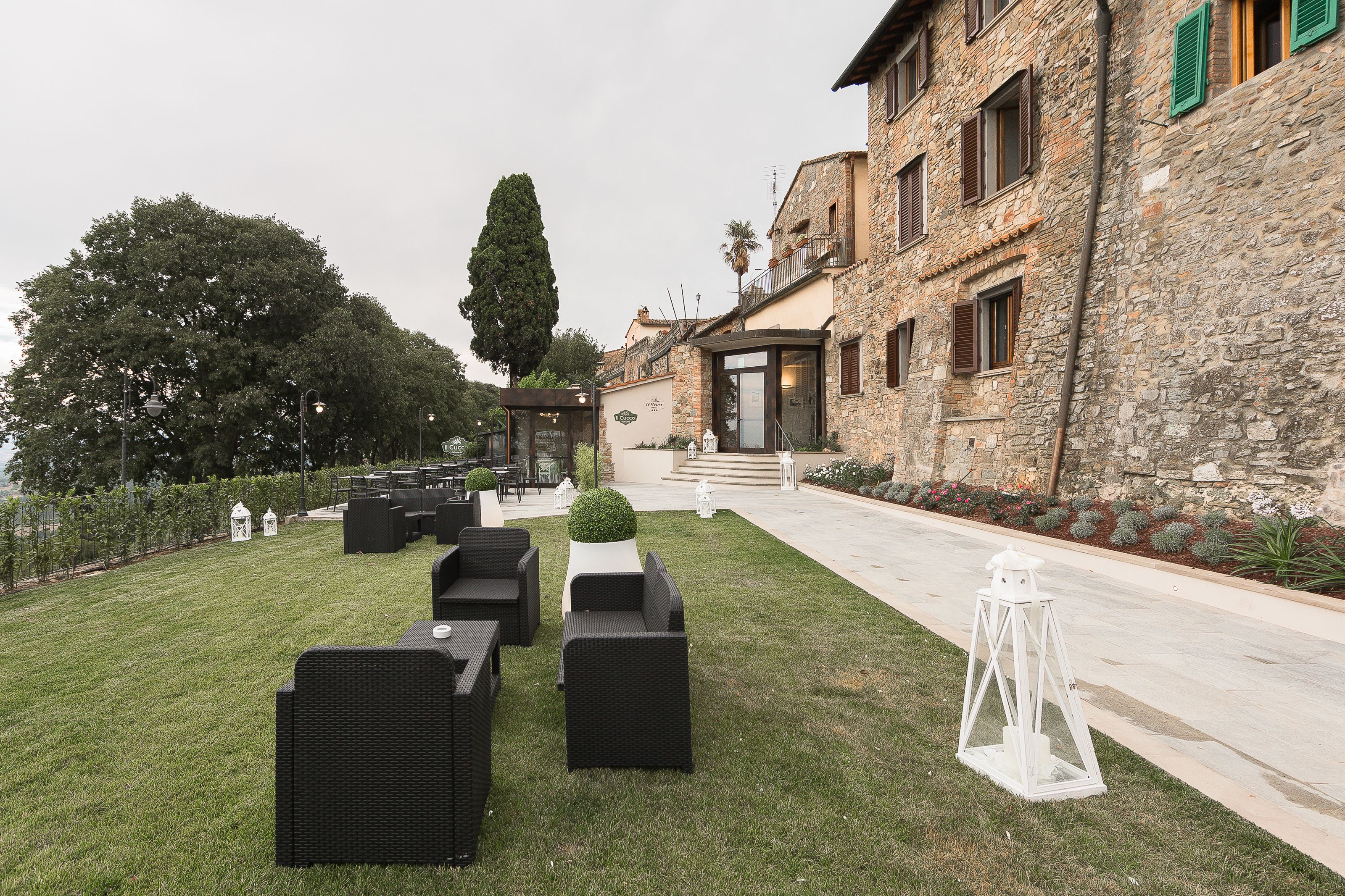 Un cortile con posti a sedere all'aperto, un edificio in pietra e un vialetto.