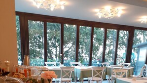A buffet setup with various food items and a view of the outdoors through large windows. - Hotel le Macine (Montaione)