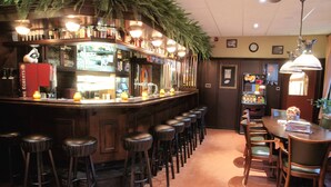 A bar area with stools, a counter, and a dining table with chairs. - Hotel Ekamper (Roodeschool)